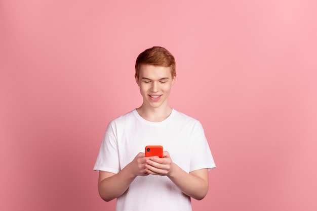 Photo of young man read post comment cellphone like follow subscribe isolated over pink color background