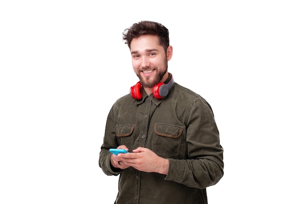Photo of young man using a smaprthone while looking cheerfully at camera over white background