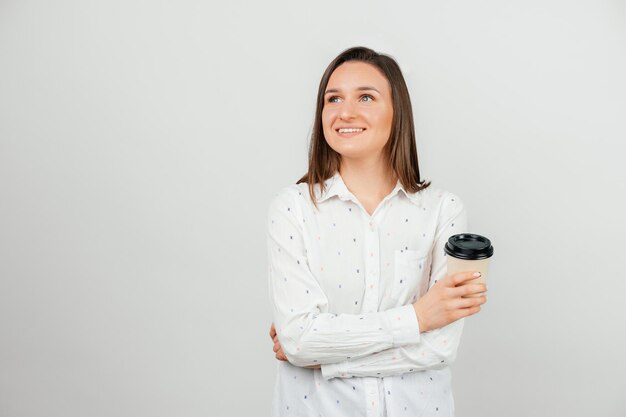 Photo of young office woman smiling and holding paper cup of coffee to go over grey background