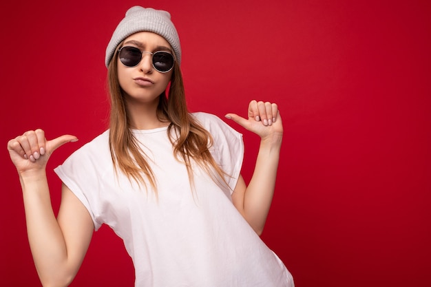 Foto di una giovane donna bionda scura attraente fresca e positiva con emozioni sincere che indossa un bianco casual