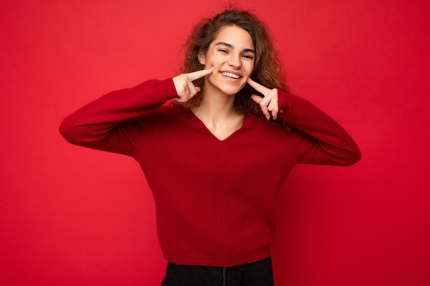 Photo of young positive happy smiling attractive brunette curly woman with sincere emotions wearing