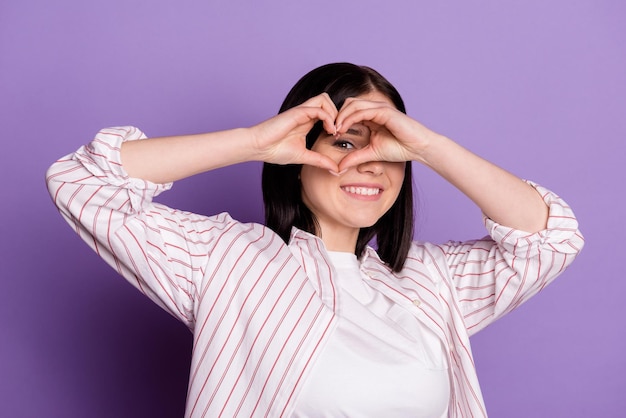 Photo of young pretty girl show fingers heart shape look eye watch cupid isolated over violet color background