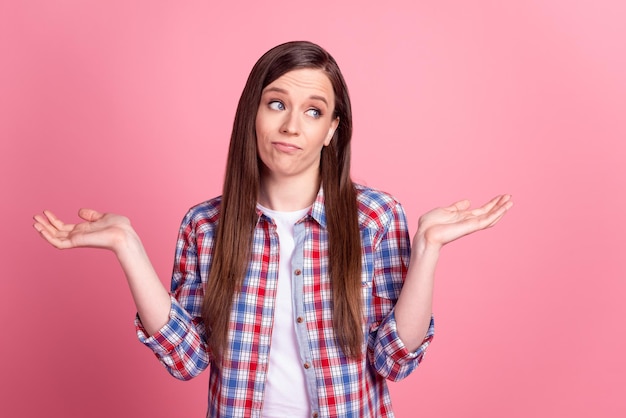 Photo of young pretty lady shrug shoulders uncertain unsure look empty space think isolated over pink color background