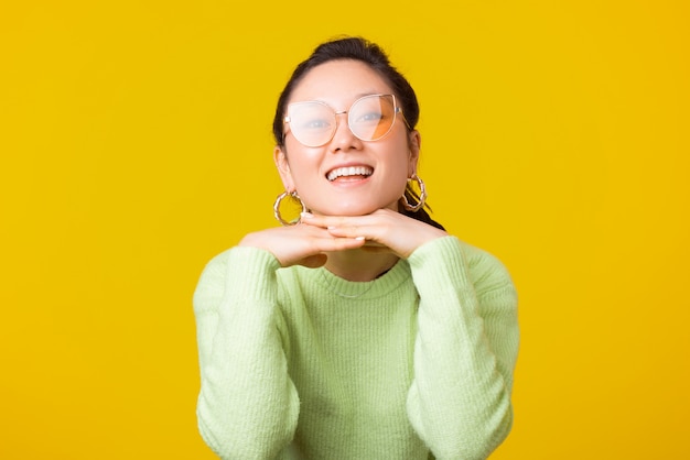 Photo of young pretty woman wearing glasses is looking at the camera on yellow space.