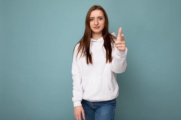 Photo of young selfconfident beautiful brunette woman with sincere emotions wearing stylish white