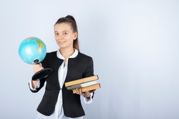 Photo of young teacher holding books and globe on white.