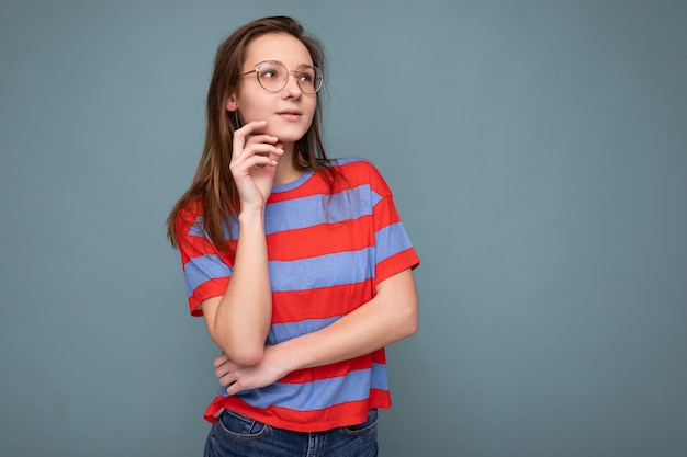 Photo of young thoughtful attractive brunette woman with sincere emotions wearing stylish striped