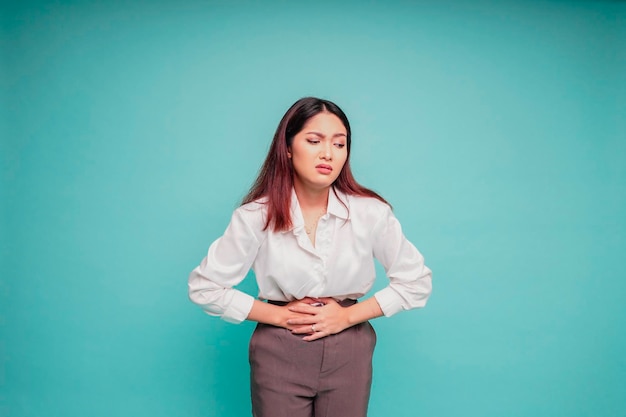 Photo of young unwell sick ill woman hold hand on stomach suffers pain isolated on blue background