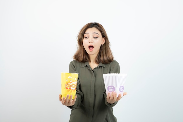 Photo of young woman in casual outfit holding popcorn. High quality photo