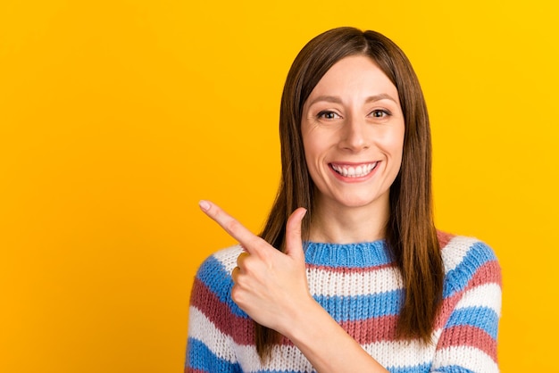 Photo of young woman dressed shirt smiling pointing finger empty space ads promo isolated on yellow color background