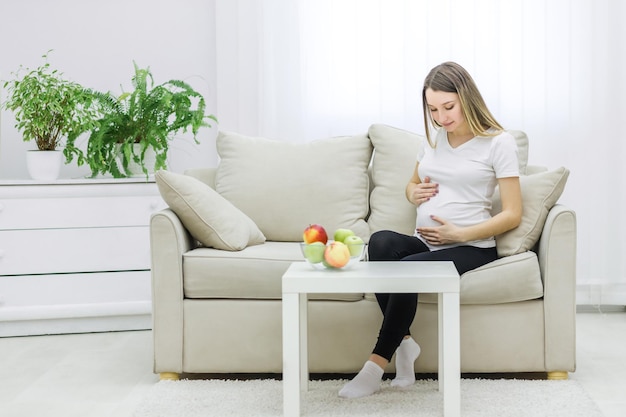 photo of young woman touching her stomach on sofa