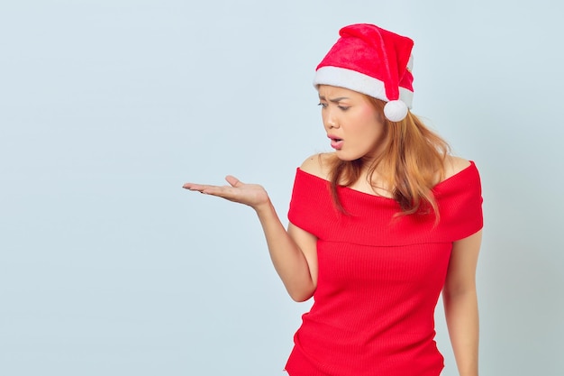 Photo of Young woman wearing christmas dress showing something with palms with surprised expression