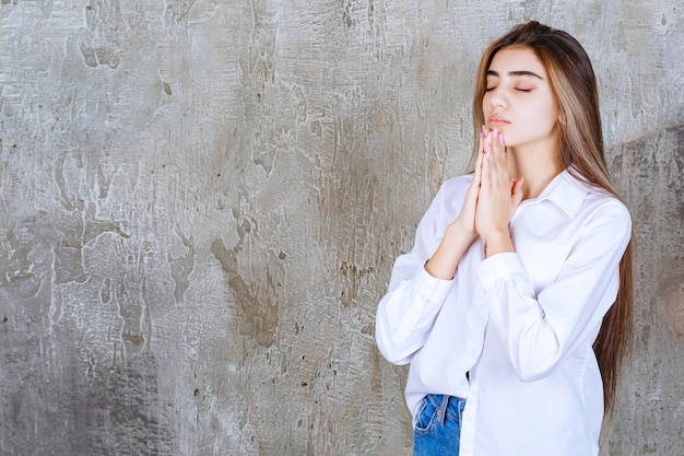 Photo of young woman in white blouse praying to God. High quality photo