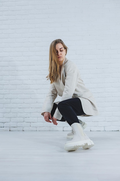 Photo of a young woman in white boots and casual clothes New collection of women's winter shoes made of genuine leather