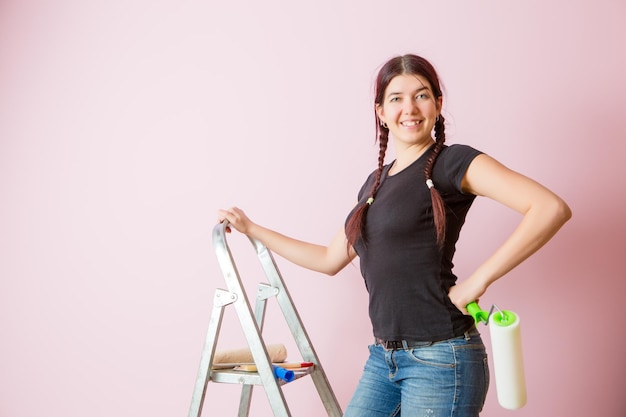 Photo of young woman with paint roller standing near staircase