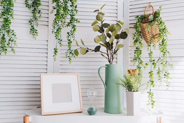 Photoframe, vase, hourglass, plants and various decorative objects on a table