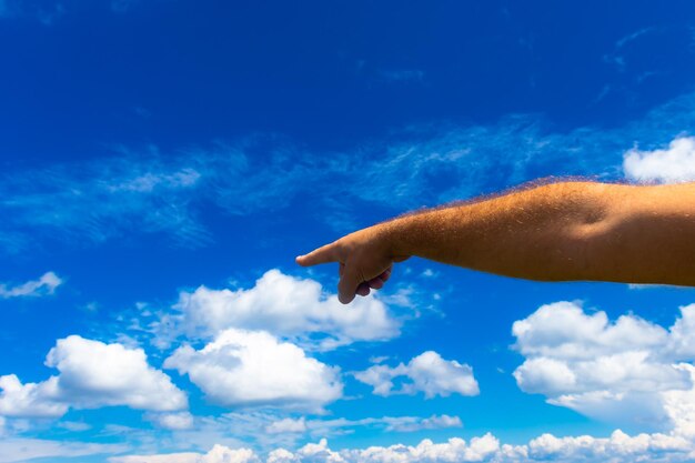 Photo photograph of a man's hand pointing in one direction against a background of blue sky