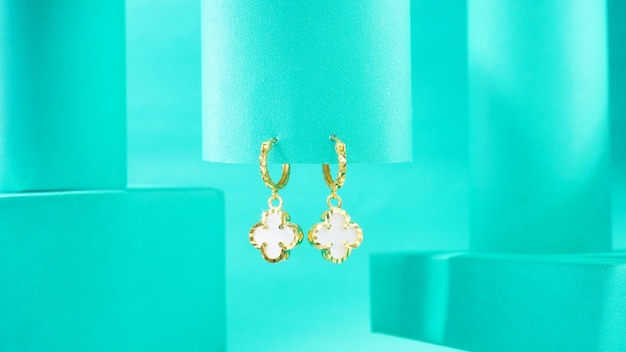 A photograph of a pair of gold earrings on a blue background