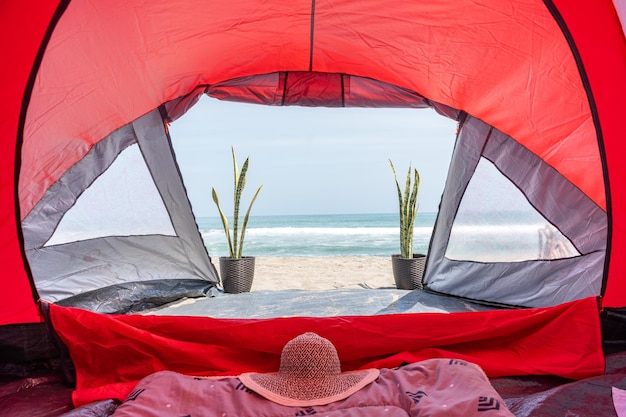 Photograph of a red camping tent on the beach at the beach by Yuri Ugarte Cespedes