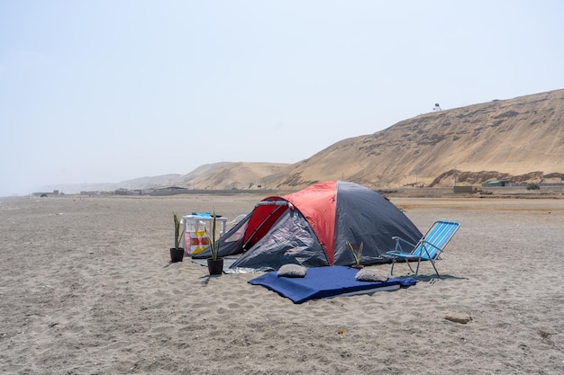 Fotografia di una tenda da campeggio rossa sulla spiaggia al tramonto di yuri ugarte cespedes