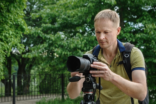 Fotografo che regola la macchina fotografica sul treppiede