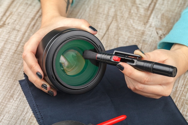 The photographer cleans the lens of the lens from dust.