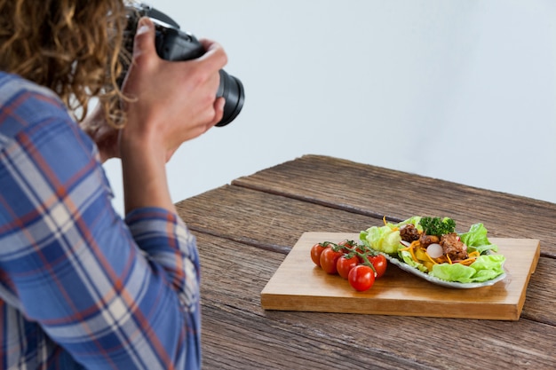 カメラマンがデジタルカメラを使用して食品の写真をクリック