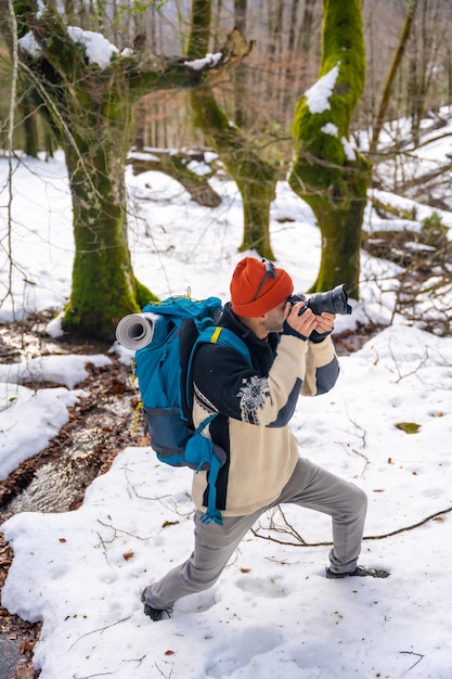 Photographer enjoying taking pictures in winter in a snowy forest winter hobbies