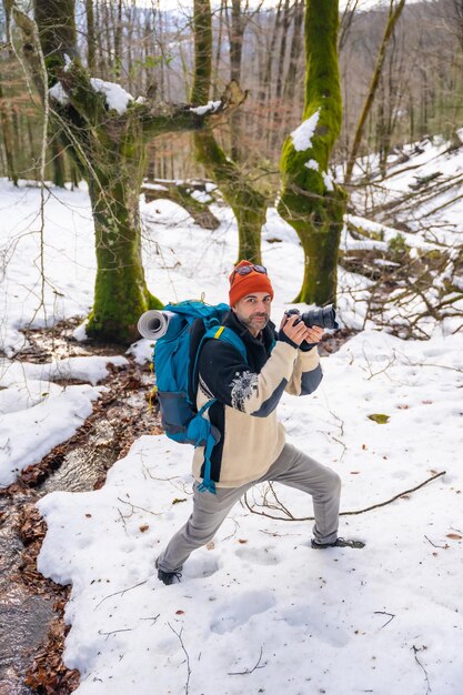 Fotografo che si diverte a scattare foto in inverno in un bosco innevato hobby invernali