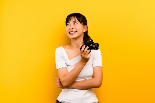 Photographer girl taking pictures Isolated model on yellow background with copy space