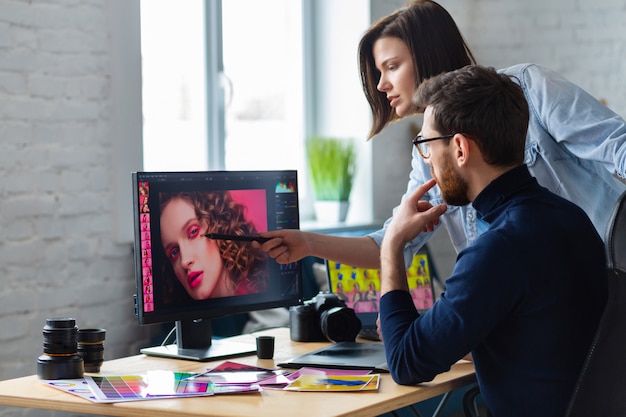 Photographer and graphic designer working in office with laptop, monitor, graphic drawing tablet and color palette.