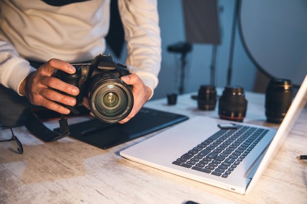 写真 テーブルの上のコンピューターと写真家の手カメラ