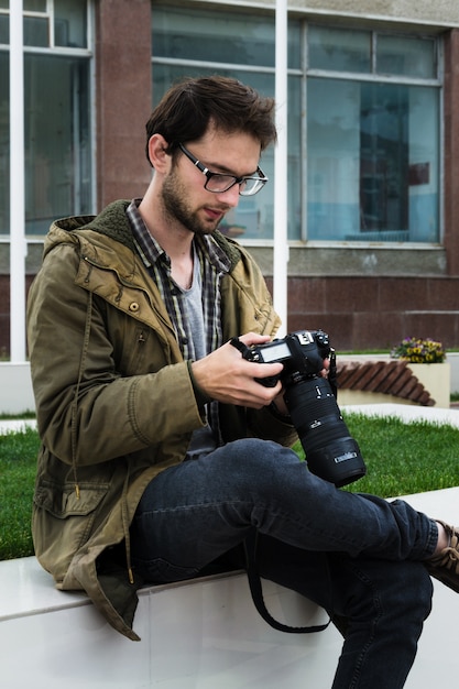 Photographer at a happy sunny day outdoor photo session near flags and bench