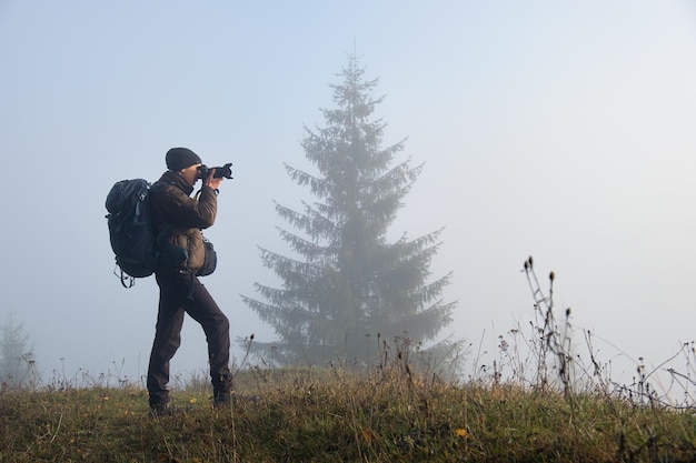 Photographer hiker taking picture of nature with digital camera