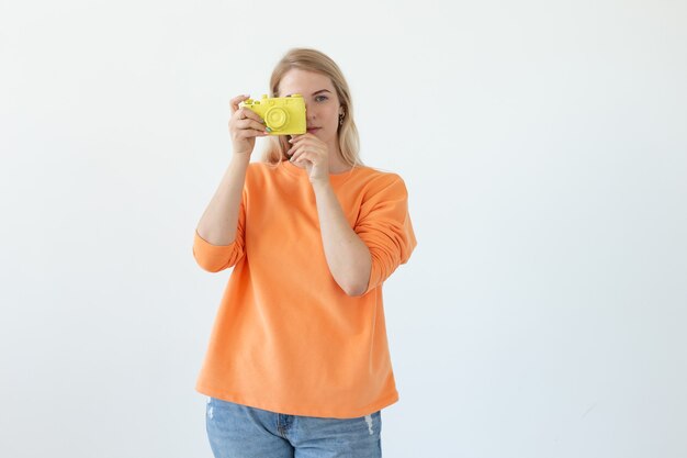 Photographer, hobby and leisure concept - Young blond woman with retro camera on white background