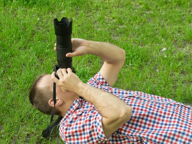 Photographer lies on the grass and takes pictures