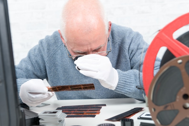 Photographer looking at negative film with a magnifying glass