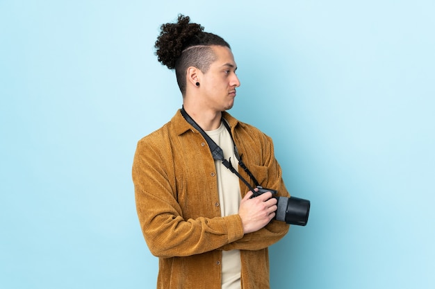 Photographer man over isolated blue looking to the side