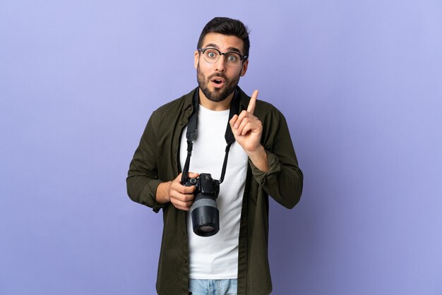 Photographer man over isolated purple background intending to realizes the solution while lifting a finger up