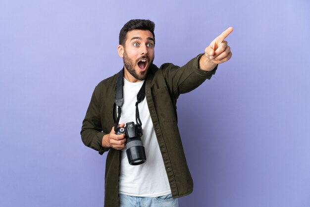 Photographer man over isolated purple background pointing away