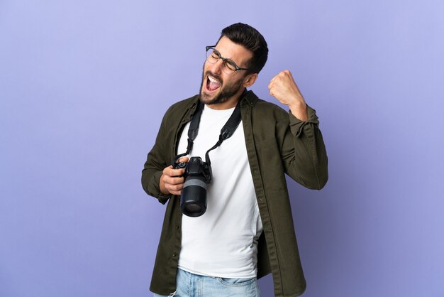 Photographer man over isolated purple celebrating a victory