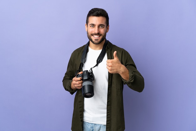 Foto l'uomo del fotografo sopra la parete viola isolata che dà pollici aumenta il gesto