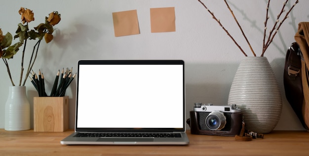 Фото Офисная комната фотографа с ноутбуком пустого экрана, канцелярскими товарами и камерой