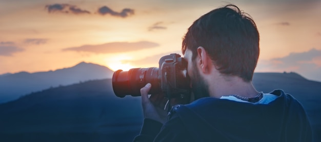 Fotografo fotografa il tramonto in montagna