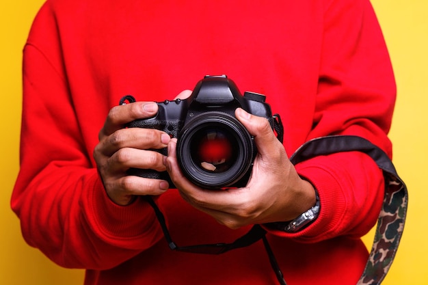 photographer in red shirt makes photos Male hands hold the camera closeup and adjust lens