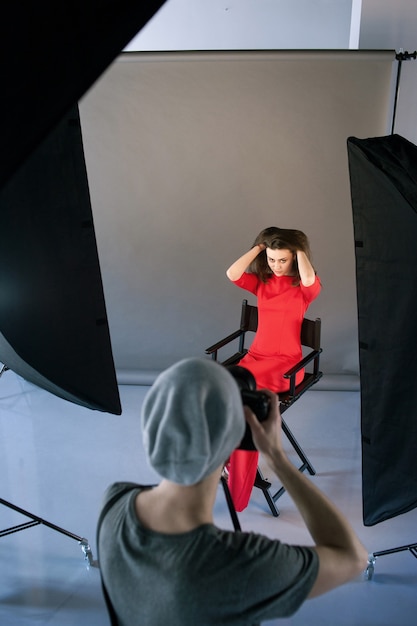 Foto il fotografo fotografa la modella in rosso durante una sessione in studio