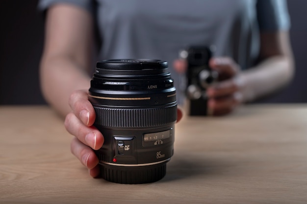 Photographer showing camera lens, blurred vintage old one and modern 85 mm lens in focus.