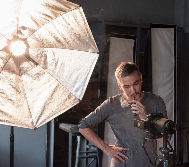 Фотограф курит сигарету во время фотосессии