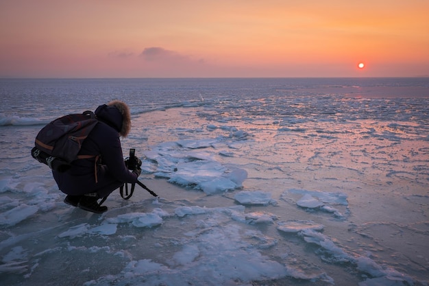 Photographer take a pictures on the ice during sunset