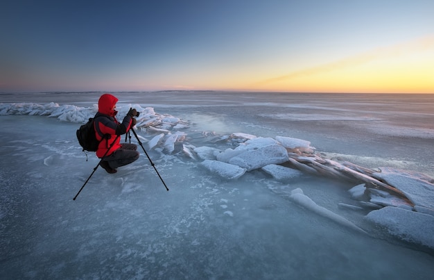 写真家は冬に川岸で写真を撮る